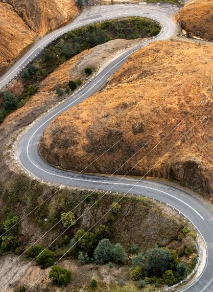 A road, the Lyell Highway, winding its way down through mostly barren hillside.