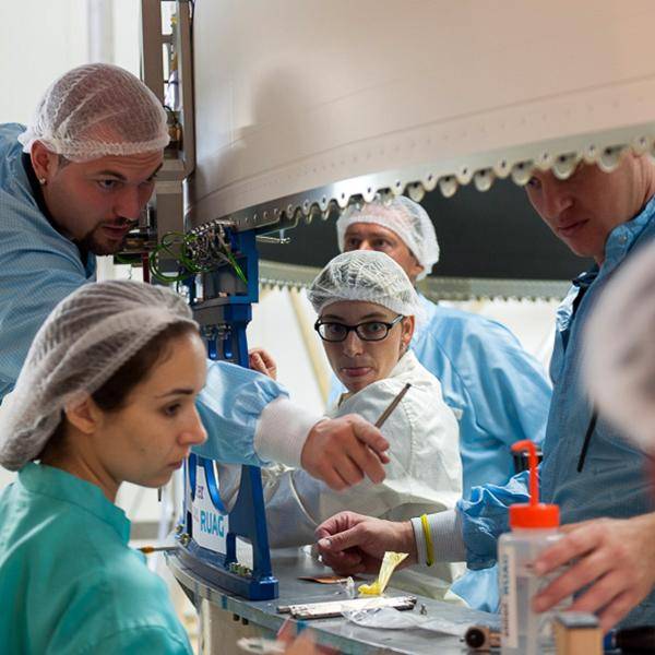 A team of people are interacting as they work on nbn's Sky Muster Satellite before launch