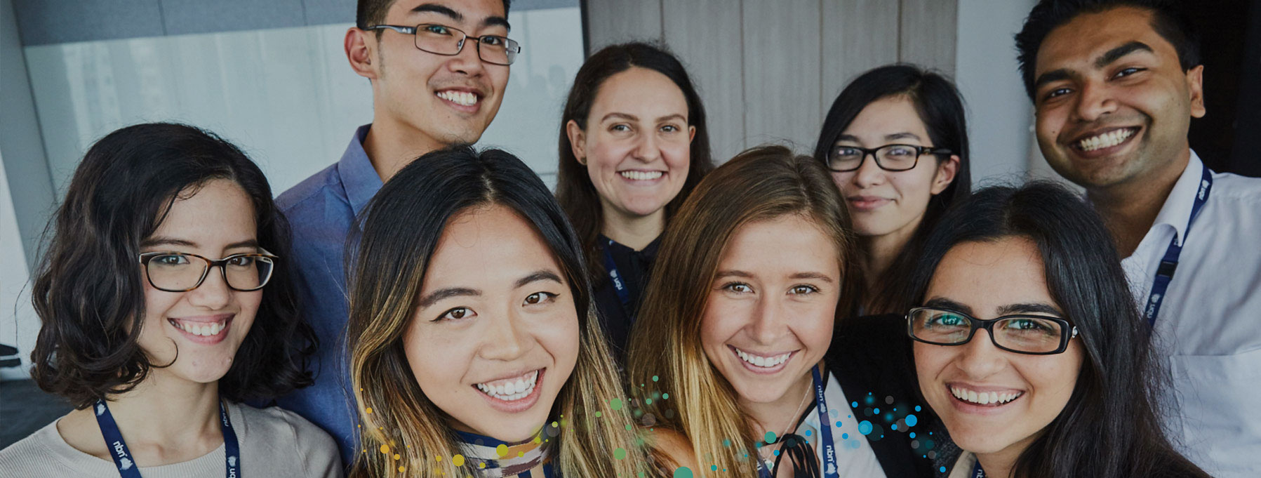 Eight members of nbn's graduate team are gathered together in the office and are smiling at the camera